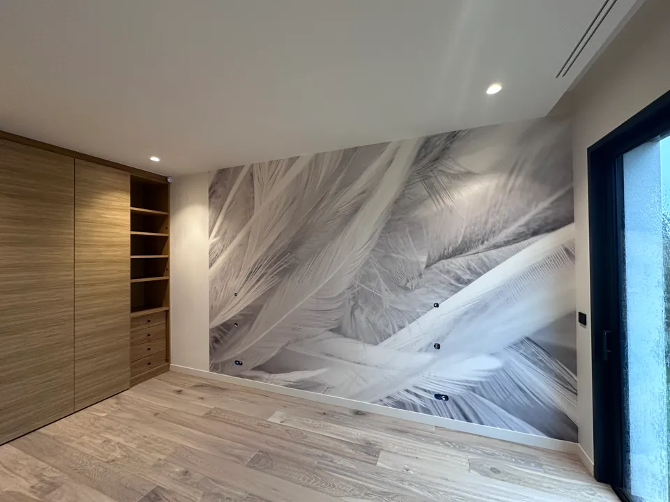 Pièce avec un papier peint panoramique à motif de plumes, placards en bois clair, parquet et grande fenêtre